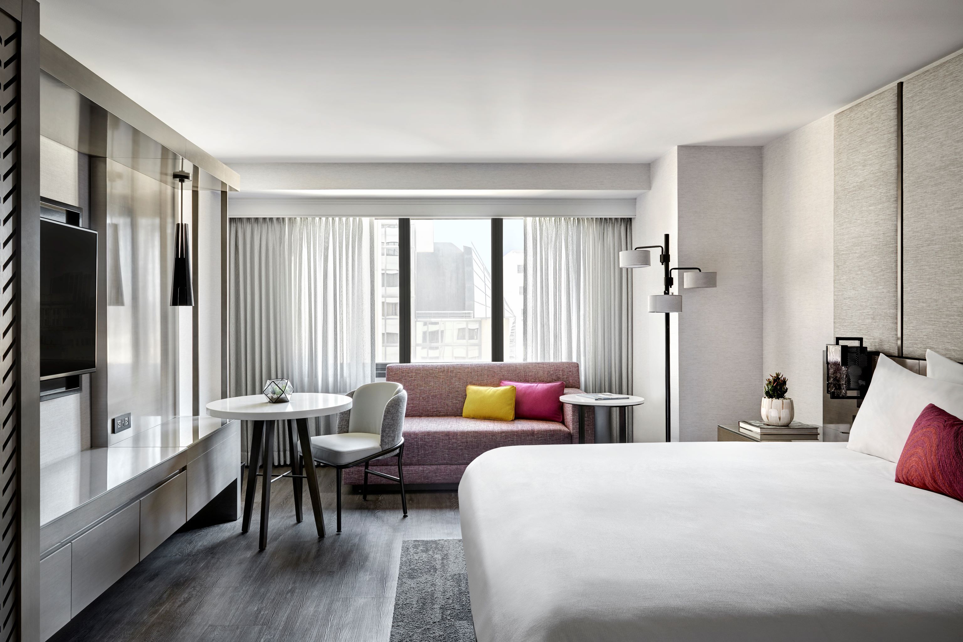 Guestroom with king bed, small table, love seat and lots of natural light